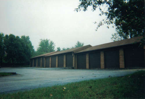 Before photo a a string of garages all needing new stain.