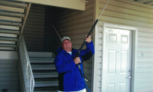 Photo of Scott powerwashing a metal hallway ceiling.