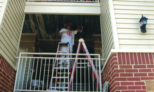 Photo from below of sanding a metal hallway ceiling.