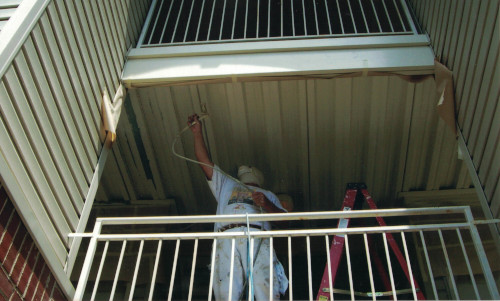 Photo from below of spray painting a hallway ceiling.