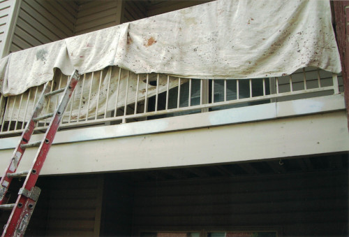 Photo of a deck's railing tarped over w/ propped up ladder.