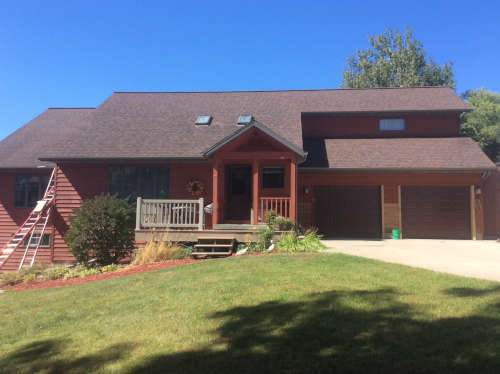Before photo of the outside of a two story country home with faded red siding.