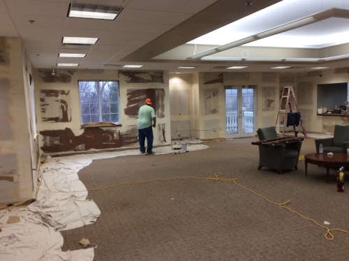 A wide photo of a the large office where the walls are being prepared for priming.