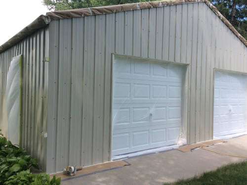 Before photo of the outside of a two story country home with faded red siding.