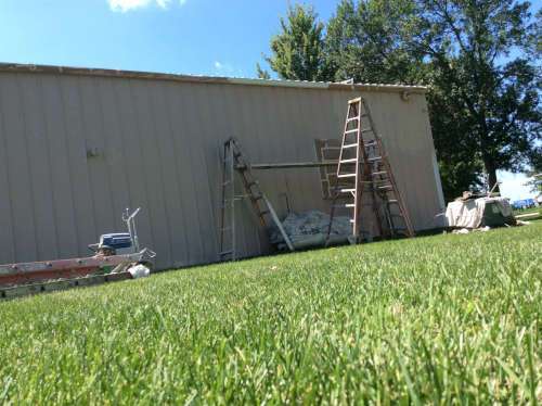 A close-up shot of Scott using a ladder secured to the roof in order to safely work this dangerous spot.