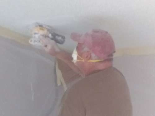 A dusty photo of Scott sanding the mudded drywall patch in the dining room ceiling.