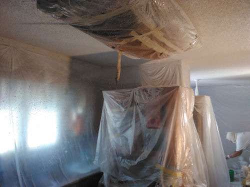The kitchen with plastic and paper masking over everything to protect it from the drywall texturing spray.